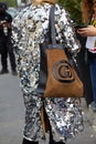 Woman with silver sequin jacket and brown and black Gucci bag before Fila fashion show, Milan