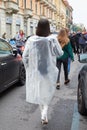 Woman with silver transparent raincoat and white boots walking before Boss fashion show, Milan