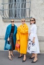 Women with blue, orange coat and white dress before Prada fashion show, Milan Fashion Week