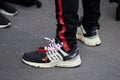 Man with black and white Nike Air shoes and black trousers with red stripe before Represent fashion show,
