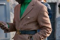 Man with brown coat and Gucci belt looking at smartphone before Emporio Armani fashion show, Milan Fashion