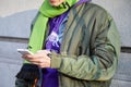 Man with green bomber jacket, scarf and purple sweater looking at phone before Marni fashion show, Milan