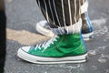 Man with green Converse All Stars glitter sneakers and black and white striped trousers before Diesel Black