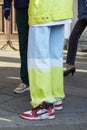 Man with red and white Nike sneaker shoes and yellow and blue jeans and jacket before MSGM fashion show, Milan