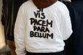 Man with white bomber jacket with latin motto `If you want peace, prepare for war` before MSGM fashion show,