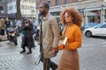 Man, woman and photographer with beige coat and orange jacket before Daks fashion show, Milan Fashion Week