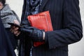 Stylish man looking at smartphone with orange crocodile baguette poses for photographers before Bikkembergs Royalty Free Stock Photo