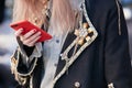 Woman black coat with golden pin, decorations and red smartphone cover before Etro fashion show, Milan Fashion