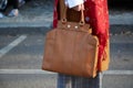 Woman poses for photographers with brown leather bag and red scarf before Giorgio Armani fashion show on Royalty Free Stock Photo