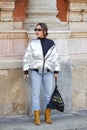 Woman with silver, metallic padded jacket and blue jeans before MSGM fashion show, Milan Fashion Week street