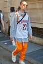 Man with Cavaliers shirt and orange trousers before Prada fashion show, Milan Fashion Week street style on June