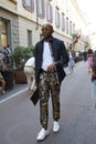 Man with golden and blue decorated trousers before Versace fashion show, Milan Fashion Week street style on June