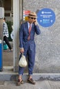 Man with Gucci shoes, blue overalls and beige hat before Marni fashion show, Milan Fashion Week street style on