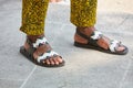 Man with open sandal shoes and yellow trousers with floral decoration before Emporio Armani fashion show, Milan