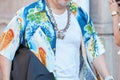 Man with oriental shirt with orange carp fish and necklace with colorful bees before Prada fashion show, Milan