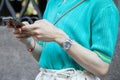 Man with Rolex watch with gray dial looking at smartphone before Versace fashion show, Milan Fashion Week street