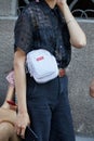 Woman with white Supreme pouch and black shirt and trousers before Les Hommes fashion show, Milan Fashion Week