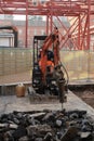 Demolition of the asphalt of a road with a jackhammer. Small excavator with demolition hammer. In the background steel trellis