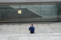 Milan - 6/17/2020 : man with mask sitting on empty steps in front the glass fountain at Apple store