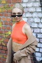 Milan, September 24, 2020: model wears an orange top and a brown jacket