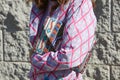 Woman with colorful beads decorated bag and pink and white checkered dress before Alberto Zambelli fashion