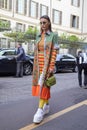 Woman with orange, green, yellow clothing and white wedge heel shoes before Antonio Marras fashion show,