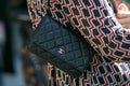 Woman with small Chanel black leather bag with golden logo before Giorgio Armani fashion show, Milan Fashion