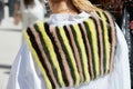 Woman with yellow, black, green and brown striped fur scarf before Alberto Zambelli fashion show, Milan