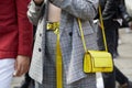 Woman with yellow leather bag and gray checkered suit before Versace fashion show, Milan Fashion Week street