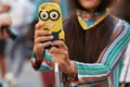 Woman with yellow Minion smartphone cover before Salvatore Ferragamo fashion show, Milan Fashion Week street