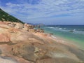 Mild colors of the pink limestone and azure waves on the distant beach