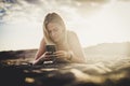 Milennial young beautiful blonde girl type on the phone lay down on the sand at the beach in outdoor nature activty - technology Royalty Free Stock Photo