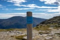 Milestone marking the way on a mountain route on a sunny day. Wooden cairn