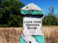 Milestone with sign Leave your sorrows behind.