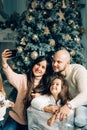 Young happy family of four taking a photo of themselves by a fireplace Royalty Free Stock Photo