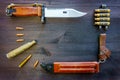 Military background: Army bayonet, cartridge cases and bullets from cartridges, bayonet sheath on a dark wooden background.