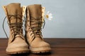 Military boots with flower on wooden surface, for text. Armed Forces Day