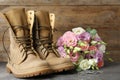 Military boots with flowers on grey surface, space for text. Armed Forces Day