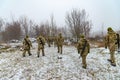 The military in camouflage with Kalashnikov assault rifles, behind their backs, go forward to attack the enemy in winter