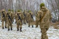 The military in camouflage with Kalashnikov assault rifles, behind their backs, go forward to attack the enemy in winter