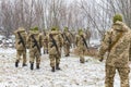 The military in camouflage with Kalashnikov assault rifles, behind their backs, go forward to attack the enemy in winter