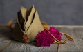 Military cap, carnations, Saint George ribbon on a wooden surface