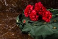 Military clothes and carnations, against the background of the monument