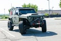 military color Jeep Wrangler is parked in a supermarket parking lot