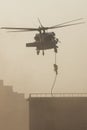 Military combat and war with helicopter flying into the chaos and destruction. Soliders suspend from rope to the ground from Royalty Free Stock Photo