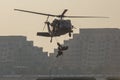 Military combat and war with helicopter flying into the chaos and destruction. Soliders suspend from rope to the ground from