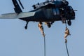 Military combat and war with helicopter flying into the chaos and destruction. Soliders suspend from rope to the ground from