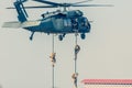 Military combat and war with helicopter flying into the chaos and destruction. Soliders suspend from rope to the ground from