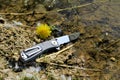 Folding knife stainless steel sharp blade black handle close up still life yellow flower water background