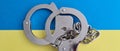 Military handcuffs on blue and yellow background of Ukrainian flag Royalty Free Stock Photo